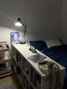 a bed room with a neatly made bed next to a book shelf and a lamp