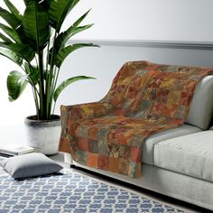 a couch sitting next to a potted plant on top of a rug