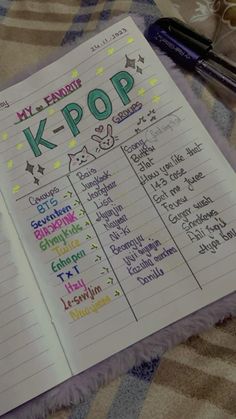 a notebook with k - pop written on it sitting on a blanket next to a pen