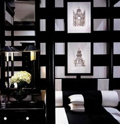 a black and white room with pictures on the wall, lamps and bed linens