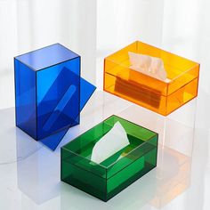 three different colored boxes with tissue paper in them