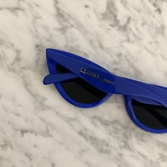 a pair of blue sunglasses sitting on top of a white marble counter with the word clinir printed on it