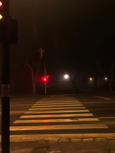 a red traffic light sitting on the side of a road next to a cross walk