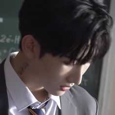 a young man wearing a suit and tie in front of a chalkboard with writing on it