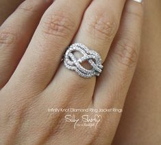 a woman's hand with a white diamond ring on her finger and the word love written