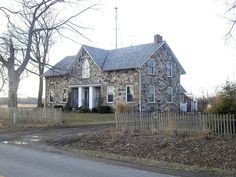 an old stone house with a picket fence around it