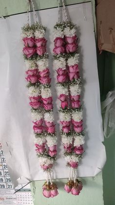 two pink and white flowers hanging from hooks