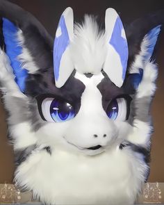 a close up of a stuffed animal with big blue eyes and white fur on it's head