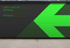 a large green arrow sign sitting on the side of a building next to a sidewalk