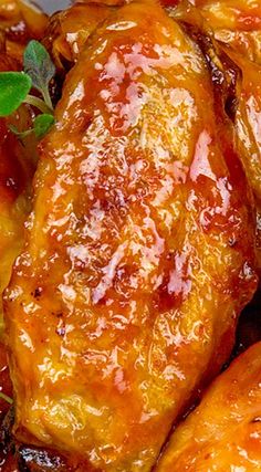 some chicken wings covered in sauce and garnished with green leaves