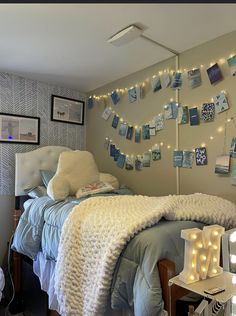 a bedroom with lights strung from the ceiling and pictures on the wall above the bed