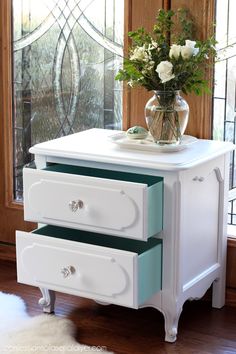 two drawers with flowers on them in front of a window and white furnishing