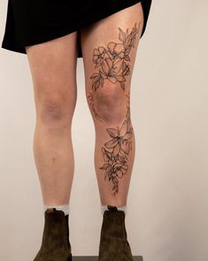 a woman's legs with tattoos on them and flowers in the middle of her leg