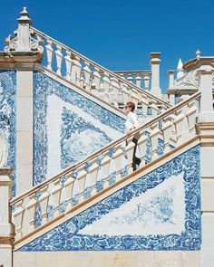 a man standing on top of a blue and white tiled stair case in front of a building