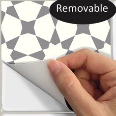 a hand is pressing the button on a white and black tile wallpaper that says removable