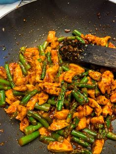 chicken and asparagus stir fry in a wok with a wooden spatula