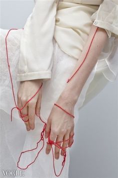 a woman's hands with red string attached to them