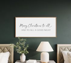 a bedroom with green walls and white bedding has a merry christmas to all sign on the wall