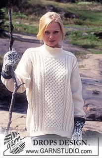 a woman is holding a stick and wearing a white knitted sweater with an intricate design