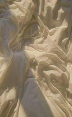 an unmade bed with white sheets and pillows