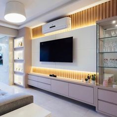 a living room with white furniture and a flat screen tv mounted on the wall above it