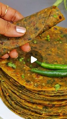 a stack of tortillas on a white plate with a green chili pepper in the middle