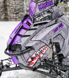 a purple and black snowmobile parked in the snow