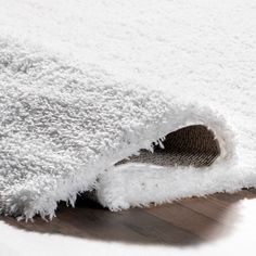 a close up of a white rug on the floor with a wooden floor underneath it