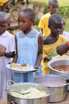 several children are standing around bowls of food