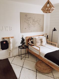 a bedroom with white walls and wood furniture, including a bed frame that has a map on the wall above it