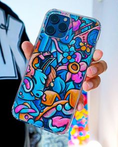 a person holding up a phone case with colorful designs on it