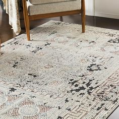 a large rug with an ornate design on the floor in front of a wooden chair