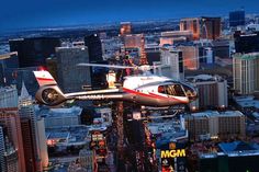 a helicopter is flying over the city at night with skyscrapers and buildings in the background