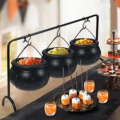 an assortment of halloween treats and drinks on a buffet table with hanging black caulders