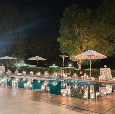 an outdoor pool with candles and umbrellas next to it