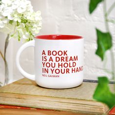 a book is a dream you hold in your hand mug on top of a stack of books