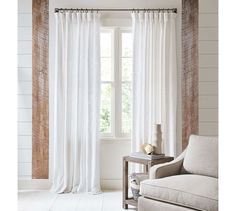 a living room with white curtains and a chair