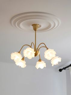 a chandelier with five lights hanging from it's ceiling in a room