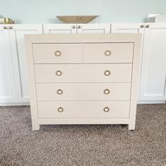 a white chest of drawers sitting on top of a carpeted floor