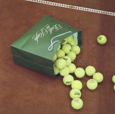 tennis balls are scattered on the ground next to a green bag