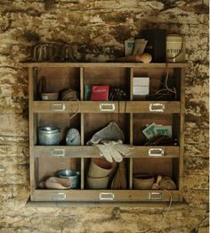 a wooden shelf filled with lots of different types of items on top of a stone wall