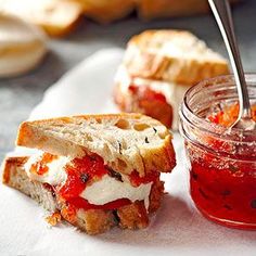 a sandwich cut in half sitting on top of a white plate next to a jar of ketchup