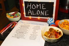 a table topped with bowls filled with food and a sign that says home alone on it