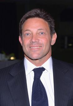 a close up of a person wearing a suit and tie with a smile on his face