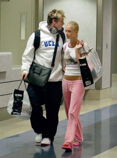 a man and woman walking through an airport with bags on their backs, one carrying shopping bags