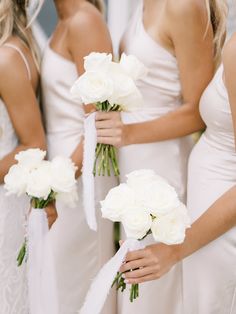 the bridesmaids are holding their bouquets with white roses on them and ribbons