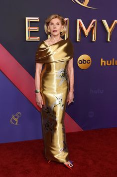 an older woman in a gold gown on the red carpet at the emmy awards,