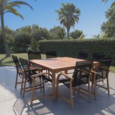 a wooden table with black chairs and palm trees in the backgroung area