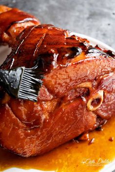 a piece of meat covered in sauce on a plate with a brush sticking out of it