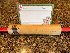 a wooden rolling pin sitting on top of a counter next to a piece of paper